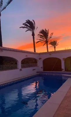 a swimming pool with palm trees and a sunset at CASITA RUSTICA DE INVITADOS (NEXT TO XATIVA) in Sellent