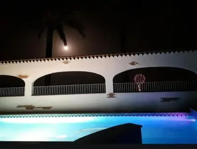 a building with a swimming pool and a palm tree at CASITA RUSTICA DE INVITADOS (NEXT TO XATIVA) in Sellent