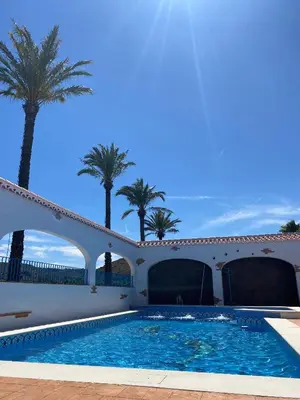a swimming pool in front of a building with palm trees at CASITA RUSTICA DE INVITADOS (NEXT TO XATIVA) in Sellent