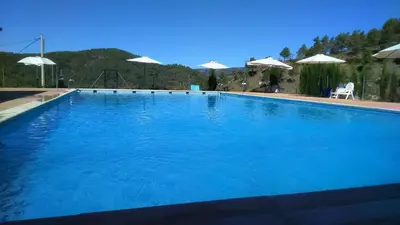 a large blue swimming pool with umbrellas at Casa de Amparo y José Manuel en Pavias in Pavías