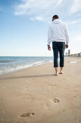 a man standing on the beach with footprints in the sand at Apartamento en primera línea de playa con vistas al mar in Mareny Barraquetas