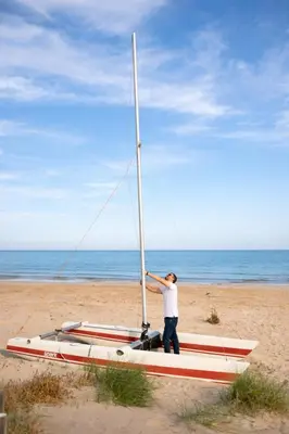 a man standing on a boat on the beach at Apartamento en primera línea de playa con vistas al mar in Mareny Barraquetas
