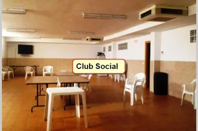 a room with tables and white chairs and a sign that reads club social at Apartamento nuevo playa de Canet de Berenguer WIFI in Canet de Berenguer