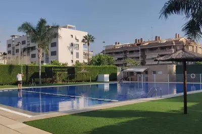a swimming pool with an umbrella and some buildings at Apartamento nuevo playa de Canet de Berenguer WIFI in Canet de Berenguer