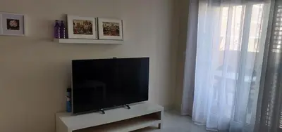 a flat screen tv sitting on a stand next to a window at Apartamento nuevo playa de Canet de Berenguer WIFI in Canet de Berenguer