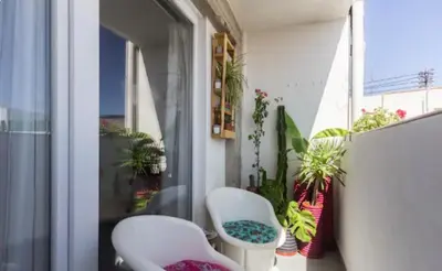 a balcony with two white chairs and potted plants at Torres de Serrano Apartment in Valencia
