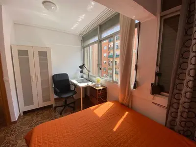 a bedroom with a bed and a desk and a window at Piso cerca de la playa - Act. Mauri 1B in Valencia