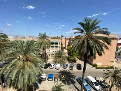 a parking lot with palm trees in front of a building at Piso cerca de la playa - Act. Mauri 1B in Valencia