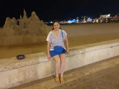 a woman sitting on a wall next to a sand sculpture at Alquiler Universidades Malvarrosa Playa Maritim Valencia Solo para familias con niños in Valencia