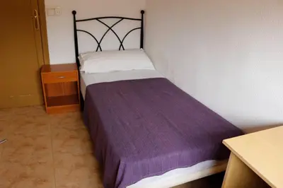 a small bedroom with a bed with a purple blanket at apartemento ideal grupo y familia climatisacion y cerca playa . mongrell in Valencia