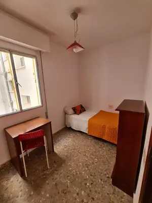 a bedroom with a bed and a desk and a window at Apartemento grupo amigo o familias : blasco ibanez C in Valencia