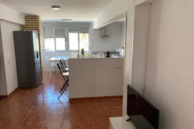 a kitchen with a refrigerator and a table with chairs at apartemento nuevo cerca playa para familia o amigos . isidro in Valencia