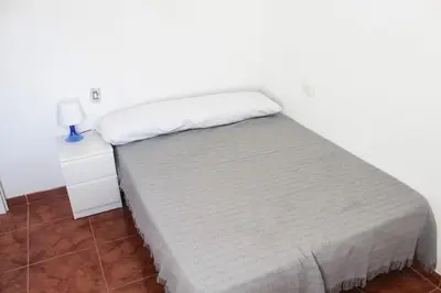 a bed in a white room with a night stand at apartemento nuevo cerca playa para familia o amigos . isidro in Valencia