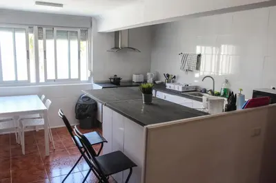 a kitchen with a counter and a table with chairs at apartemento nuevo cerca playa para familia o amigos . isidro in Valencia