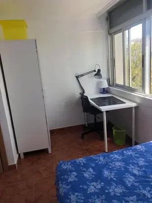 a room with a desk and a table with a lamp at apartemento nuevo cerca playa para familia o amigos . isidro in Valencia