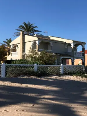 a house with a fence and a palm tree at Beach House Villa Roca in Cullera