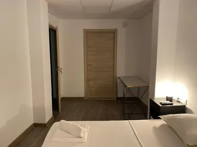 a bedroom with a bed and a desk and a door at Shanti Rooms in Valencia