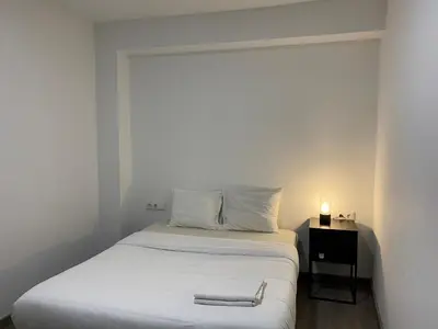 a small bedroom with a bed with white sheets and a lamp at Shanti Rooms in Valencia