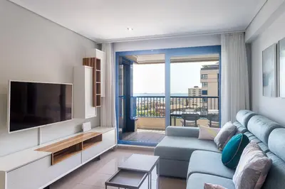 a living room with a blue couch and a tv at ApartUP Patacona Essence in Valencia