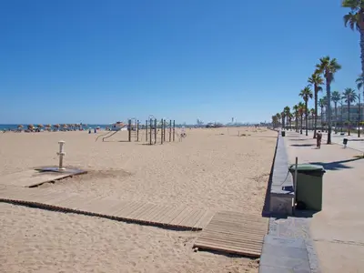a sandy beach with palm trees and a playground at ApartUP Patacona Essence in Valencia