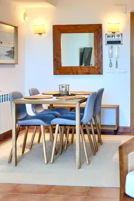 a dining room table with blue chairs and a mirror at Casa frente al mar con piscina privada in Sagunto
