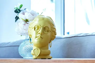 a gold head with glasses and a vase of flowers at Design, beach and city center in Valencia