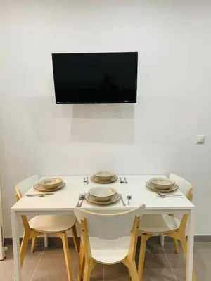 a white table with chairs and a television on a wall at UIM Mediterraneo PB Segorbe Wifi in Puerto de Sagunto