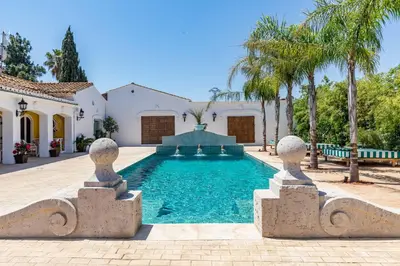a swimming pool in front of a house with palm trees at Maison San Alfredo B&B in El Puig
