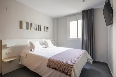 a bedroom with a bed with white sheets and a window at Stancia Carmen in Valencia