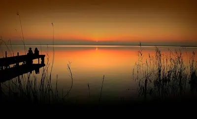 two people sitting on a dock at the end of a lake at Mareny Blau, primera linea de playa in Mareny Blau
