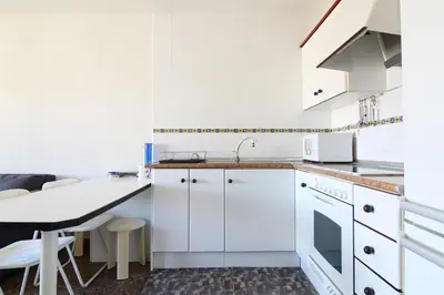 a kitchen with white cabinets and a table at Global Vacacional, Estudio para parejas con piscina en Canet playa in Canet de Berenguer