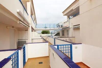 a corridor of an apartment building with blue railing at Global Vacacional, Apartamento con piscina en playa Corinto in Sagunto