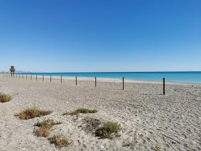 a beach with a fence in the sand and the ocean at Global Vacacional, Apartamento con piscina en playa Corinto in Sagunto