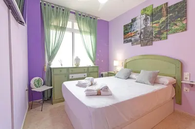a bedroom with a large bed with purple walls at Global Vacacional, Estudio para parejas en la playa del Puerto de Sagunto in Puerto de Sagunto