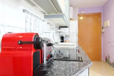 a red suitcase sitting on top of a kitchen counter at Global Vacacional, Estudio para parejas en la playa del Puerto de Sagunto in Puerto de Sagunto