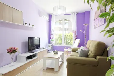 a living room with purple walls and a couch and a tv at Global Vacacional, Estudio para parejas en la playa del Puerto de Sagunto in Puerto de Sagunto