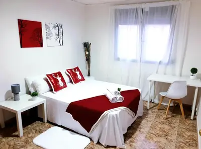 a white bedroom with a bed with red pillows at Hotel M5 Valencia Aeropuerto in Manises