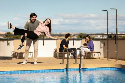 a woman jumping in the air next to a swimming pool at Resa Patacona in Valencia