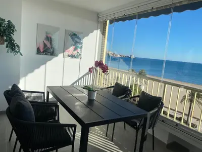 a dining room table with chairs and a view of the ocean at 1a línea con PISCINA Nuevo in Cullera