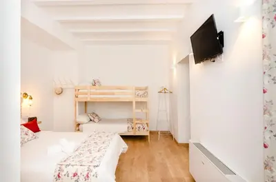 a white bedroom with a bed and a tv on a wall at PALACIO Boutique in Anna