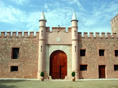 a large brick building with a large wooden door at Masía de San Juan Casas número 3 y 5, con piscina, aire acondicionado y vistas a la montaña in Segorbe