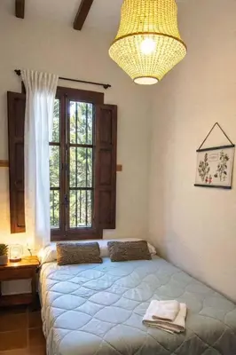 a bedroom with a large bed and a window at Masía de San Juan Casas número 3 y 5, con piscina, aire acondicionado y vistas a la montaña in Segorbe
