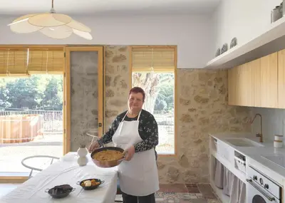 a woman in a kitchen holding a bowl of food at Villa Serrano, La casa rural de los mil suelos in Valencia