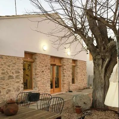 a table and chairs next to a tree and a building at Villa Serrano, La casa rural de los mil suelos in Valencia