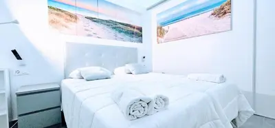 a white bedroom with a large white bed with towels on it at A45 ViviendaTurísticaValencia Mundo in Valencia
