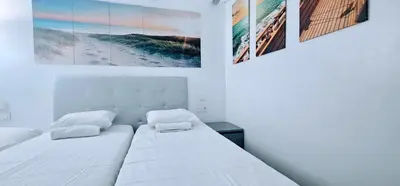 a bedroom with a white bed with two pictures on the wall at A45 ViviendaTurísticaValencia Mundo in Valencia