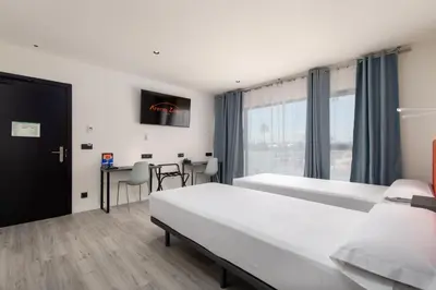 a hotel room with two beds and a table at Arena Zone Hotel in Valencia