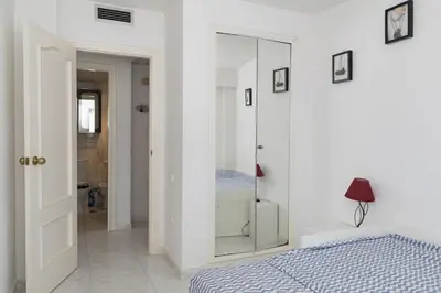 a white bedroom with a bed and a mirror at Florazar-3, 14-E in Cullera