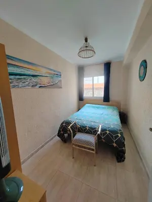 a bedroom with a bed and a chair in it at Tout près de la plage in Puerto de Sagunto