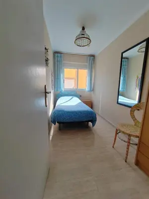 a bedroom with a bed and a mirror and a chair at Tout près de la plage in Puerto de Sagunto